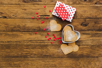 Wall Mural - Heart shaped cookies with gifts over wooden background. Valentine day - homemade festive decorated pastry biscuits cookies