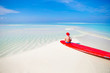 © travnikovstudio - Little girl in Santa hat on white beach during Chrismas vacation