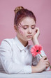 © Olena_Molchanova - Portrait of beautiful young woman looking at camera with a flower. Close up face of beauty girl with flower gerbera on pink background. Skin care and beauty concept.