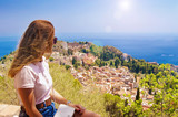 Fototapeta  - The girl looks from the heights to the city, Sicily, Taormina.No recognizable face