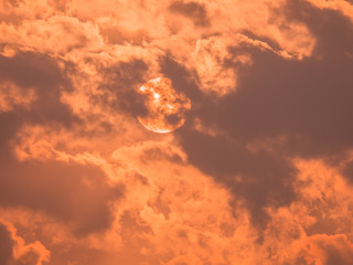 The sun behind the cloud in the morning of sunrise with the golden sunlight in cloudy sky