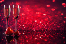 Two Glasses Of Champagne With Red Heart Shape Bokeh On Background.