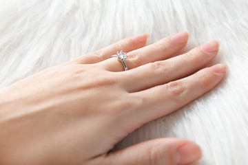 Wall Mural - Woman's hand with luxury engagement ring on fur, closeup