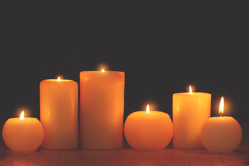 Wall Mural - Burning candles on table against black background