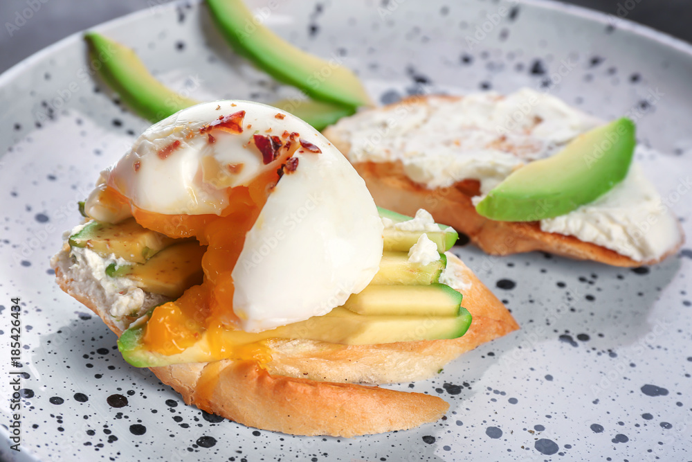 Tasty bruschetta with egg and avocado on plate, closeup