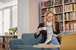 © HD92 - one woman, one person 40 years old, holding coffee cup, reading magazine, in library, book store, book shop, sitting in sofa. Shelf full of books behind (out of focus).