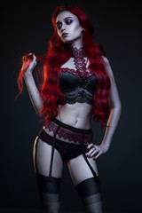 Beautiful gothic woman in lingerie posing at camera on black background