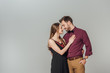 © LIGHTFIELD STUDIOS - elegant young couple smiling each other isolated on grey