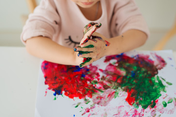 Wall Mural - Little asian girl painting with paintbrush and colorful paints