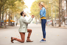 Young Man With Engagement Ring Making Proposal To His Beloved Girlfriend Outdoors