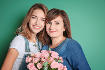 Canvas Print - Attractive young woman with her mother on color background