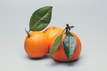 Three Tangerines With Green Leaves On A White Background
