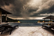 © Annatamila - Storm coming up and dark clouds above Swimming pool with sea view in luxury villa, weather and rainy season