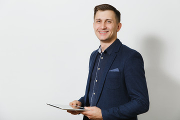 Handsome professional smiling caucasian young business man in blue classic suit and shirt holding and working in tablet isolated on white background. Manager or worker. Copy space for advertisement.