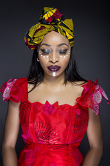 Wall Mural - Black female showing African pride by wearing Nigerian traditional clothing and tribal makeup or face painting.  The model is shot in studio in modern vogue fashion style.