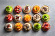 Tasty colorful cakes on grey background, top view