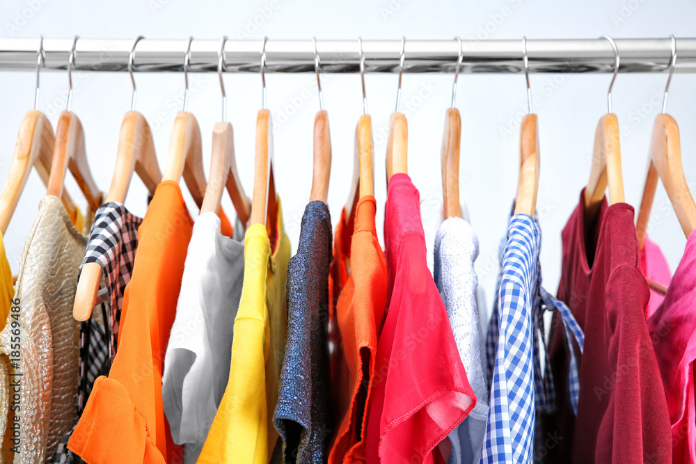 Colorful clothes on hangers in wardrobe