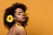 © LIGHTFIELD STUDIOS - Young bright african american woman with artistic make-up and gerbera in hair dreaming isolated on orange background