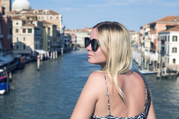 Attractive girl in sunglasses on a bridge in Venice on the background of the famous Grand Canal