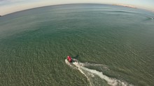 A man in Santa Claus costume rides on jetsurf beside beautiful ocean coast Aerial view