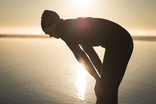 Woman In Wetsuit Bending Near Coast