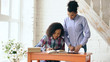 © silverkblack - Teenage curly haired mixed race young girl sitting at the table concentrating focused learning lessons and her elder sister helps her studying
