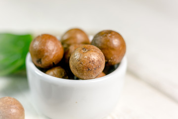 Sticker - White ceramic bowl with macadamia nuts over the wooden table.