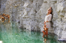 A Young Beautiful Girl With A Floral Wreath On Her Head Stands In A Pond Of Green Water. The Musical Water Beauty Poses For The Camera With An Old Vintage Violin.