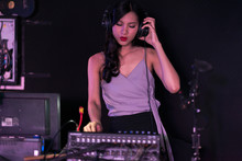 Woman DJ Party Concept. Young Chinese Woman DJ Mixing Music On Colorful Background Listening To Her Music. Selective Focus With Blurred Background.
