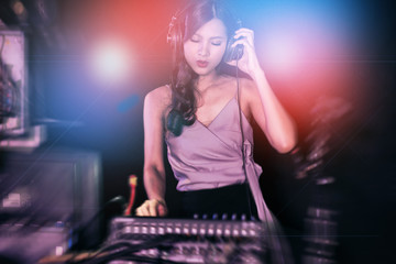 Woman DJ party concept. Young Chinese woman DJ mixing music on colorful background listening to her music. Selective focus with blurred background.