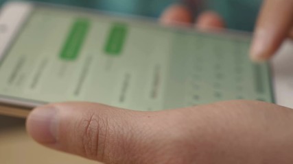 A man writes a texting SMS message using a smartphone. Male texting with mobile telephone at home, typing text message on cell phone. The screen is blurred. Close-up.