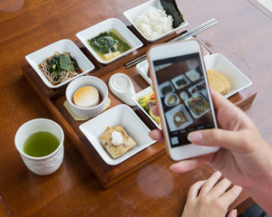 Wall Mural - woman takes photo on cell phone of japanese food.