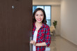 Cheerful asian woman inviting people to enter in home