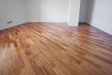 Flooring from a parquet oak board in an interior with bright light from a window.