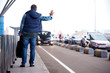 © Yakobchuk Olena - Full length back view of adult man with backpack is standing near road while raising hand. He is trying to catch car. Copy space in the right side. Selective focus