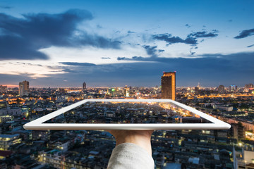 Augmented reality, hand holding digital tablet with Bangkok city skyscraper in evening