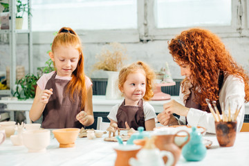 redhad Mother and two kid daughter at home molded from clay and play together