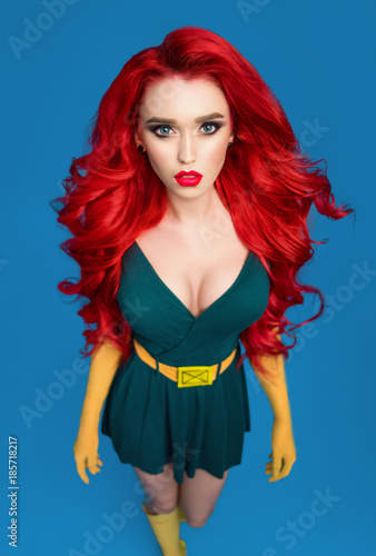 Photographie Beautiful woman in green superhero costume posing at camera on blue background