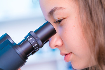 Sticker - schoolgirl girl looks through a microscope at a biology class at a gymnasium