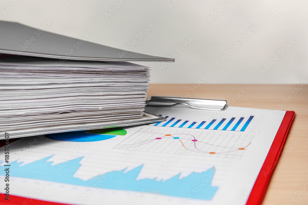 Folder and clipboard with documents on table