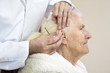 Czyszczenie uszu starej kobiecie patyczkiem. Higiena i opieka nad osobą starą.