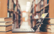 © Chinnapong - E-learning and e-book digital technology in education concept with computer notebook open in library among old stacks of book, textbook archive collection