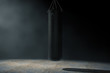 Black Leather Punching Bag for Boxing Training in the Volumetric Light. 3d Rendering