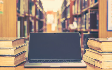 Education e-learning class and e-book digital technology concept with computer notebook screen open in school library among old stacks of book, textbook archive collection