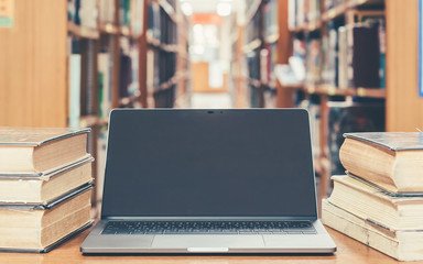 Education e-learning class and e-book digital technology concept with computer notebook screen open in school library among old stacks of book, textbook archive collection
