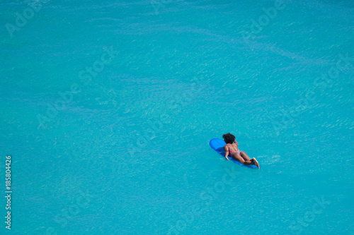 Surfer Girl With Afro Hairstyle Paddling Out On Surfboard In
