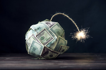 Bomb of money hundred dollar bills with a burning wick. Little time before the explosion. Concept of financial crisis