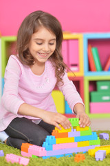 Wall Mural - Cute girl playing with plastic blocks