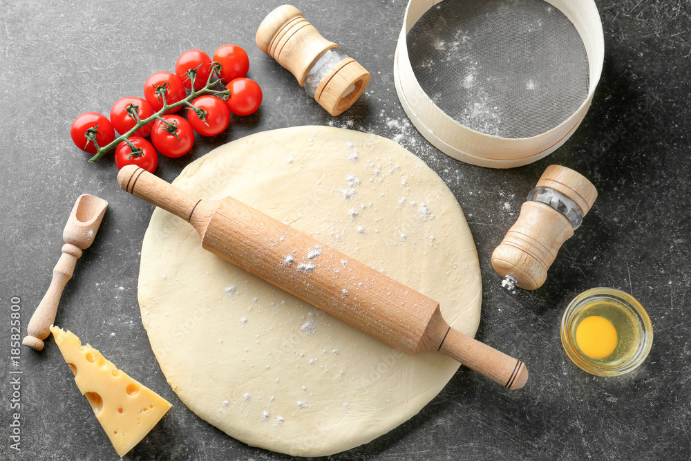 Raw dough and ingredients for pizza on table