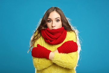 Beautiful young girl in yellow sweater, red gloves and scarf on blue background